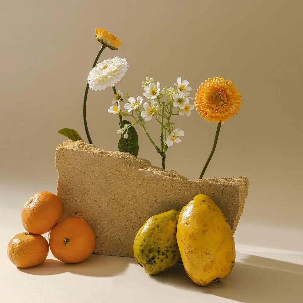 Composizione con fiori, mandarini e papaie. Fiori in un blocco di pietra.