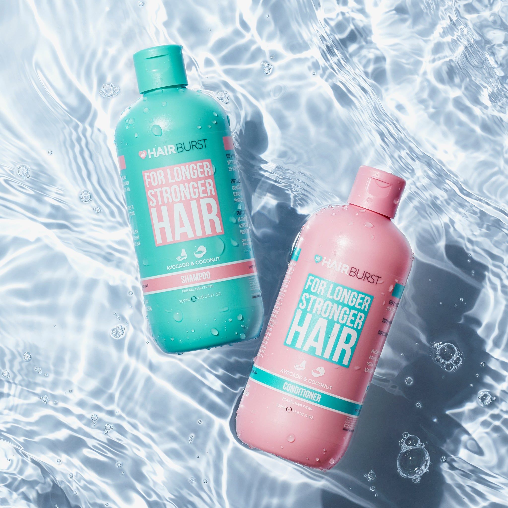 Due bottiglie di shampoo e balsamo nell'acqua. Turchese e rosa, con 'Hairburst' e 'For Longer Stronger Hair'.