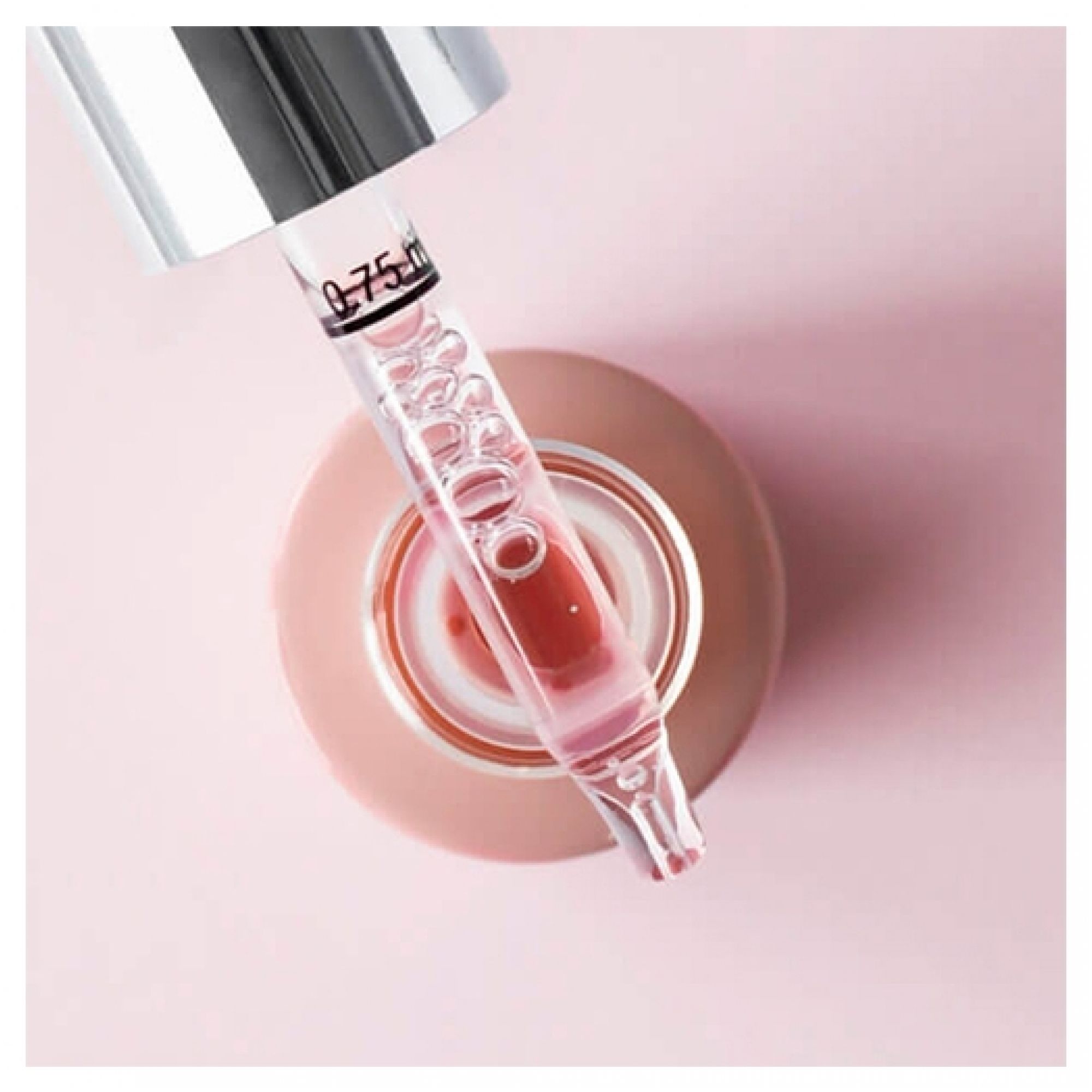 Primo piano di una testa di pipetta con siero rosa e bolle, abbassata in un flacone aperto contrassegnato 0,75 ml.