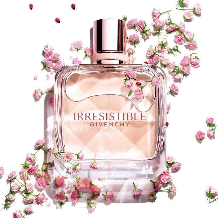 Flacone quadrato in vetro con contenuto rosa, circondato da fiori e foglie rosa. Scritta "IRRESISTIBLE GIVENCHY".