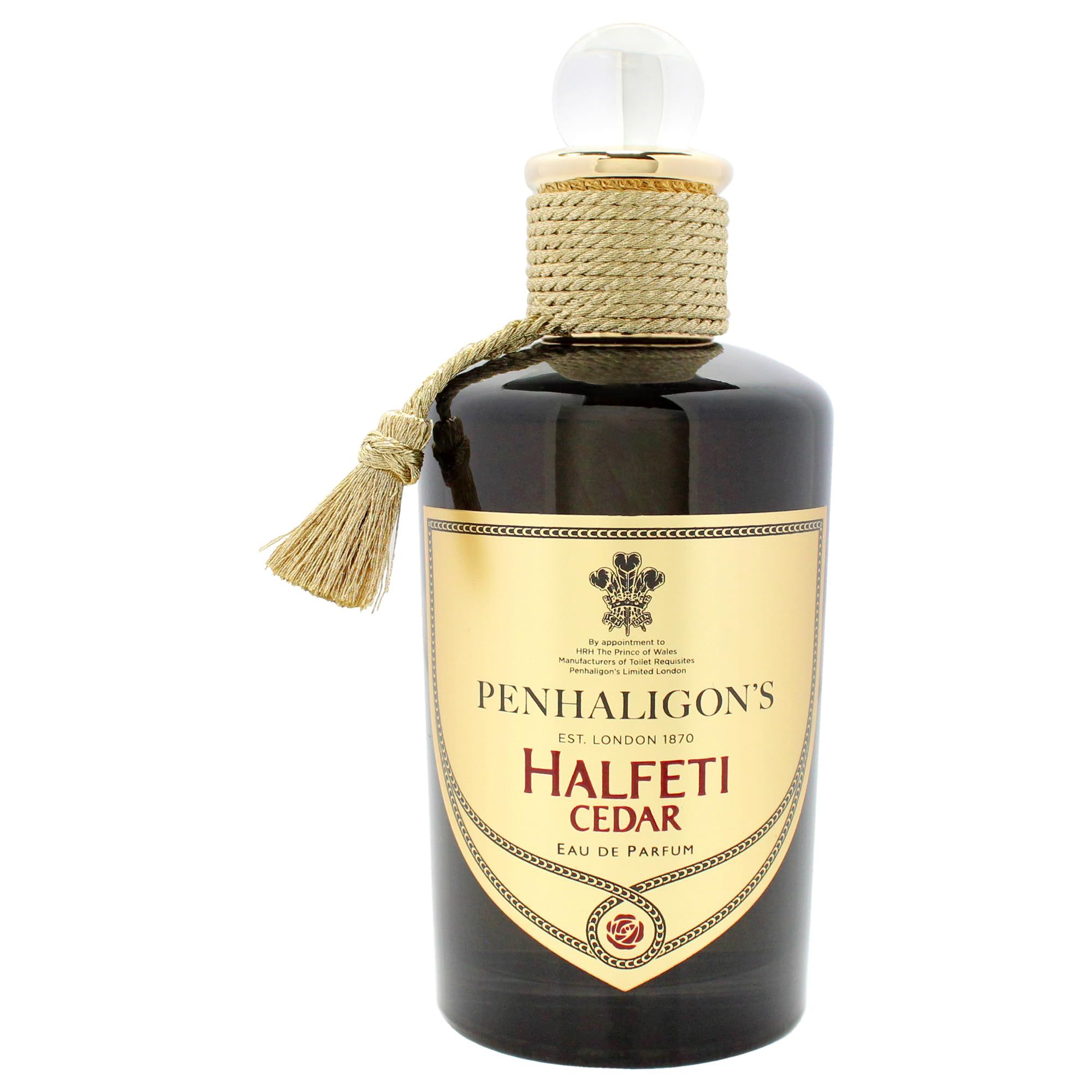 Flacone di profumo con nappa e corda. Flacone scuro con etichetta dorata e testo. Chiusura trasparente.