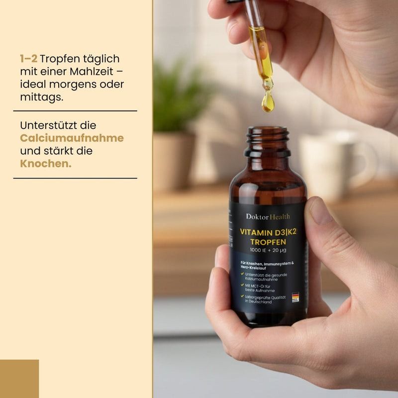 Mani che tengono un flacone di vetro marrone con contagocce. Gocce che cadono nel flacone. Scritta: Vitamin D3 + K2 Tropfen.