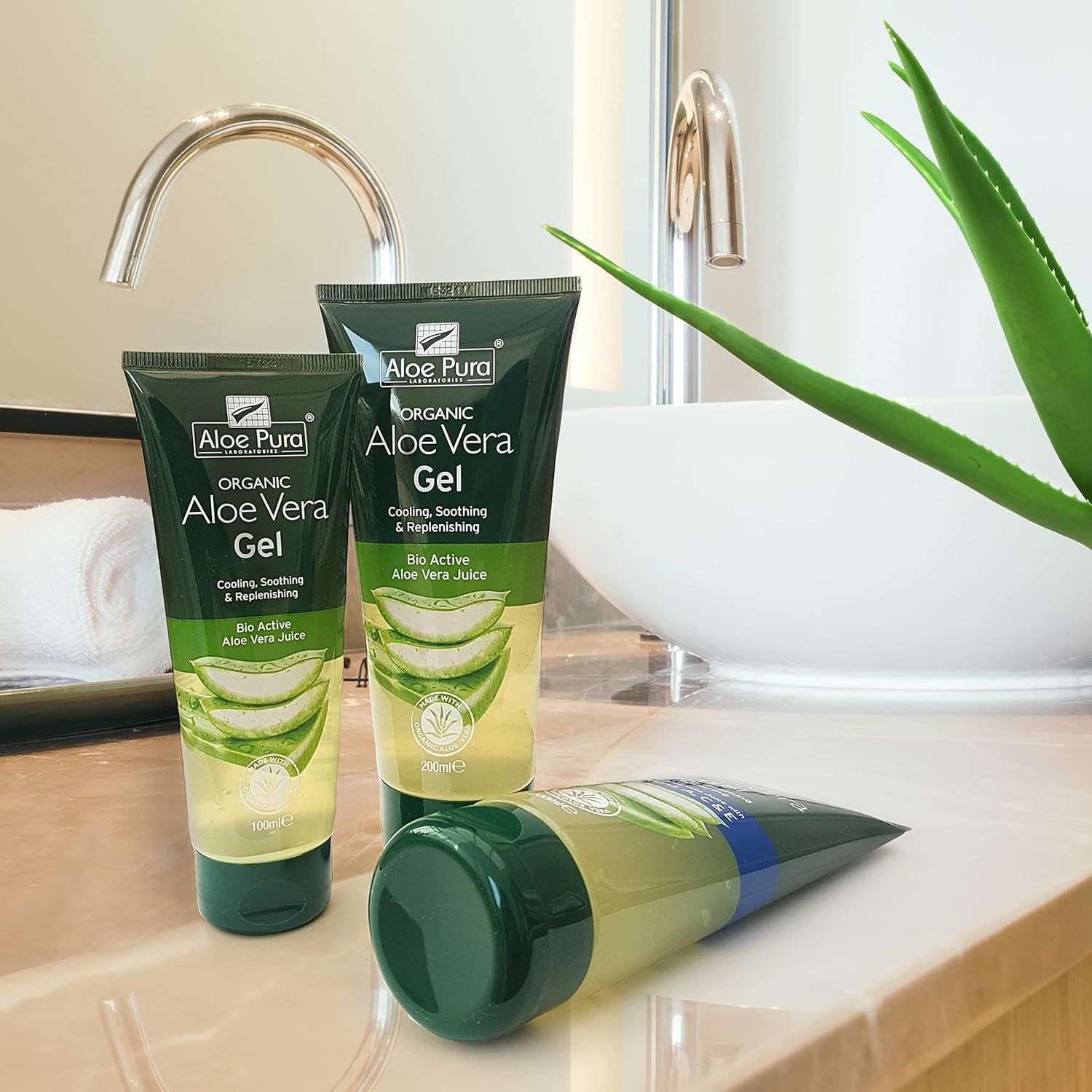 Tre tubi di gel di Aloe Vera Aloe Pura. Iscrizione: Gel di Aloe Vera biologico. Su un bancone in un bagno.