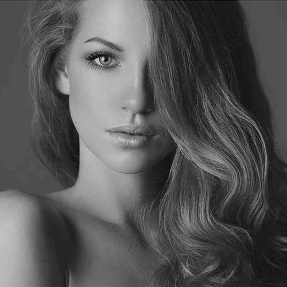 Ritratto in bianco e nero di una donna con lunghi capelli ondulati che coprono parte del viso.