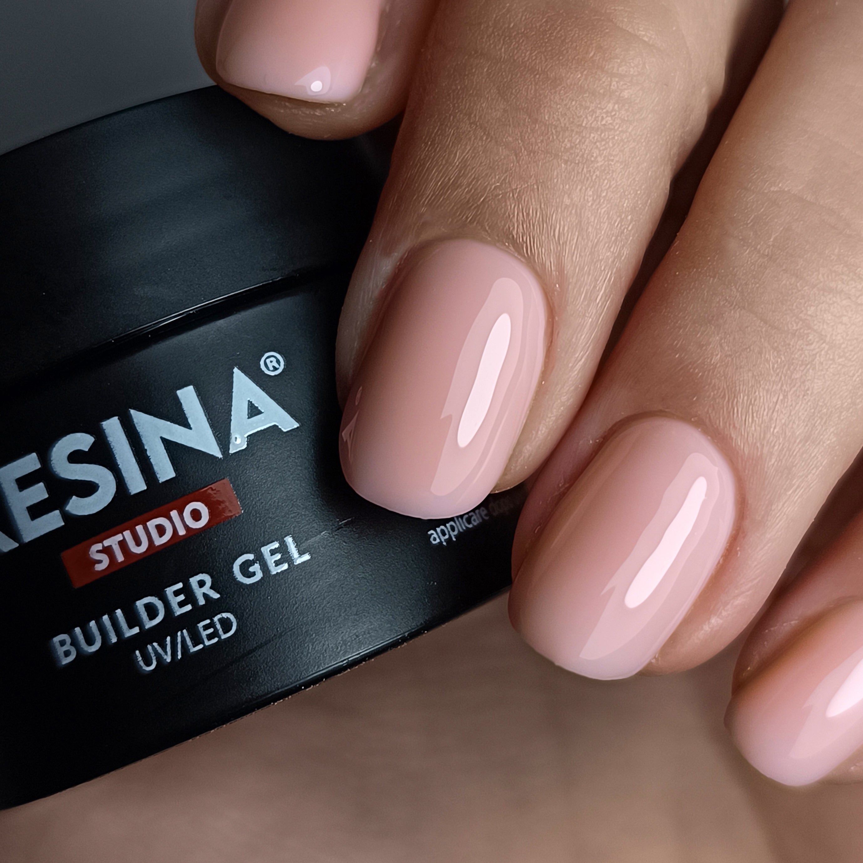 Mano con unghie smaltate rosa. Accanto, vasetto nero con scritta bianca RESINA STUDIO, BUILDER GEL UV/LED.