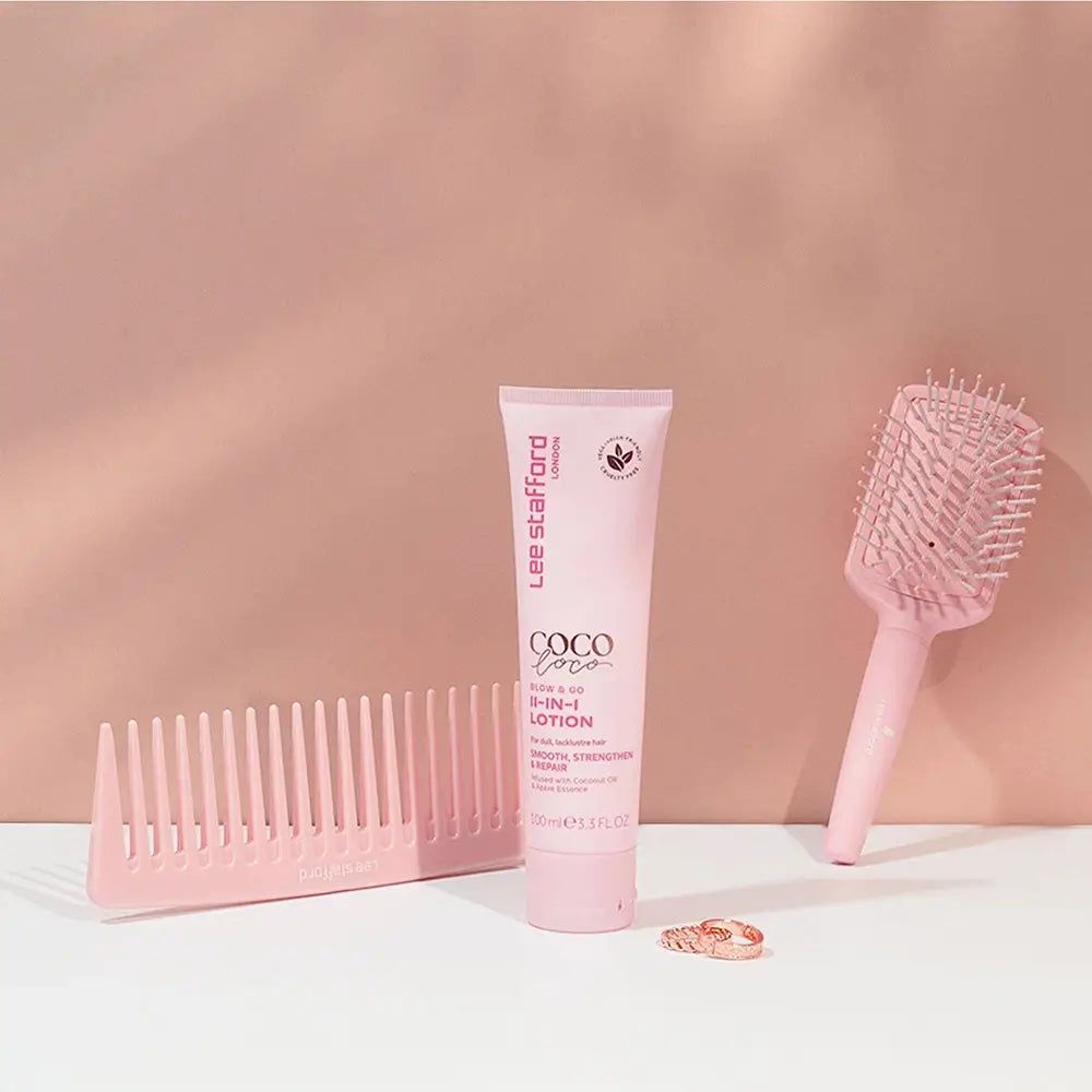 Lee Stafford Coco Loco Blow & Go Lozione 11-in-1 con pettine e spazzola per capelli su sfondo rosa.