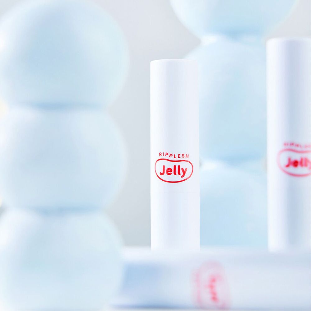 Diversi stick di balsamo labbra bianchi con logo rosso "Ripplesh Jelly". Alcuni stick sono sfocati sullo sfondo.