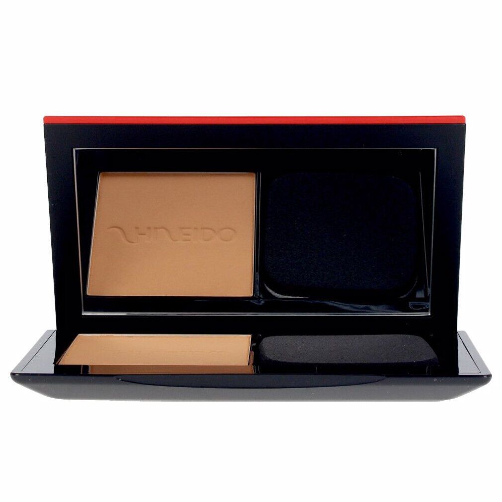 Cipria compatta con spugna. Custodia nera con dettaglio rosso. Marchio Shiseido visibile.
