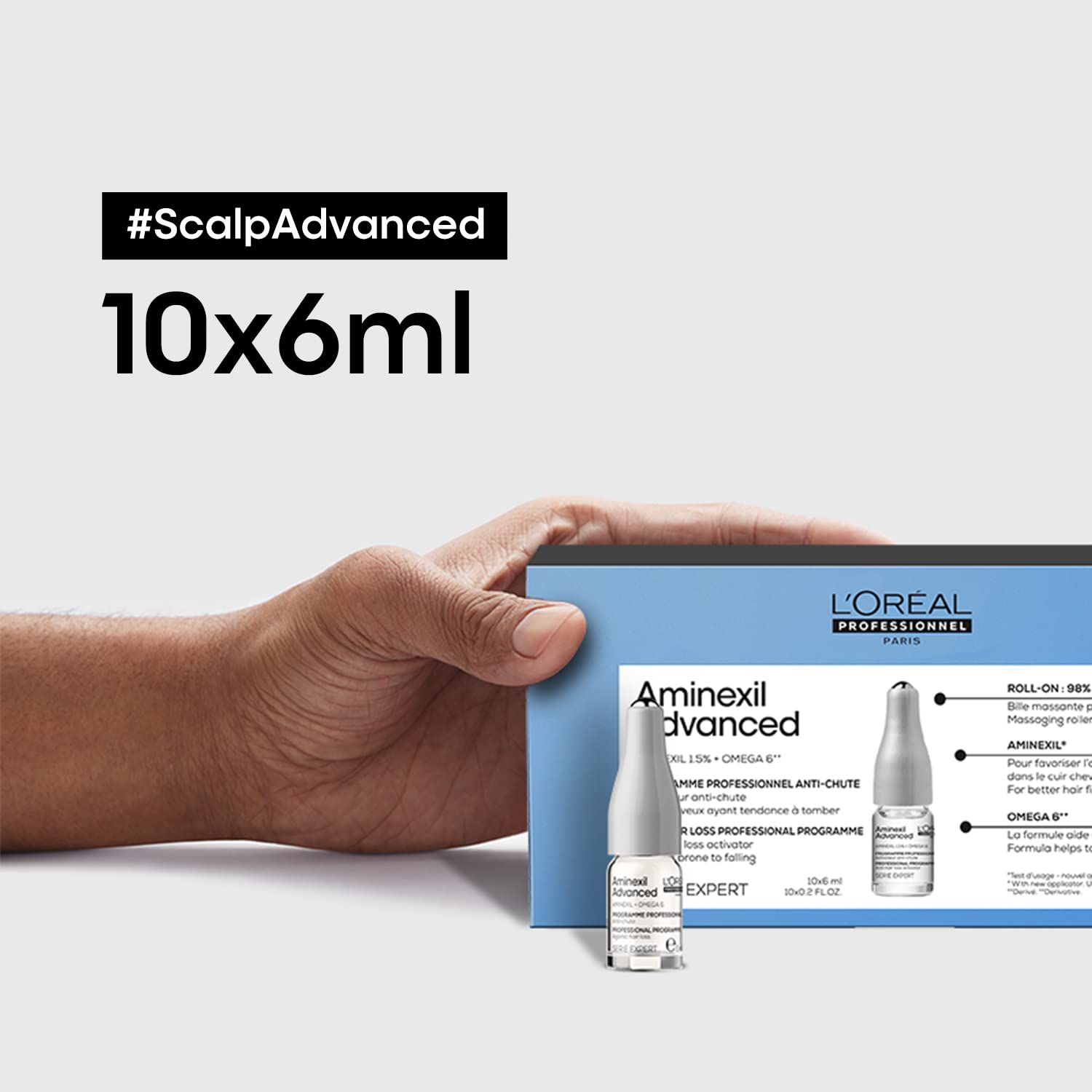 Mano che tiene una scatola di fiale. L'Oréal Professionnel Aminexil Advanced. 10 x 6 ml.