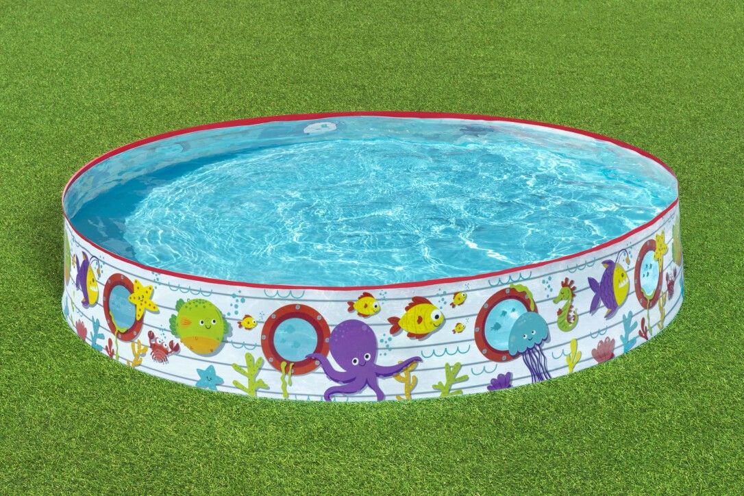 Piscina rotonda per bambini con motivo sottomarino. Bordo rosso, acqua blu. Decorazioni con pesci, polpi e stelle marine. Su erba.