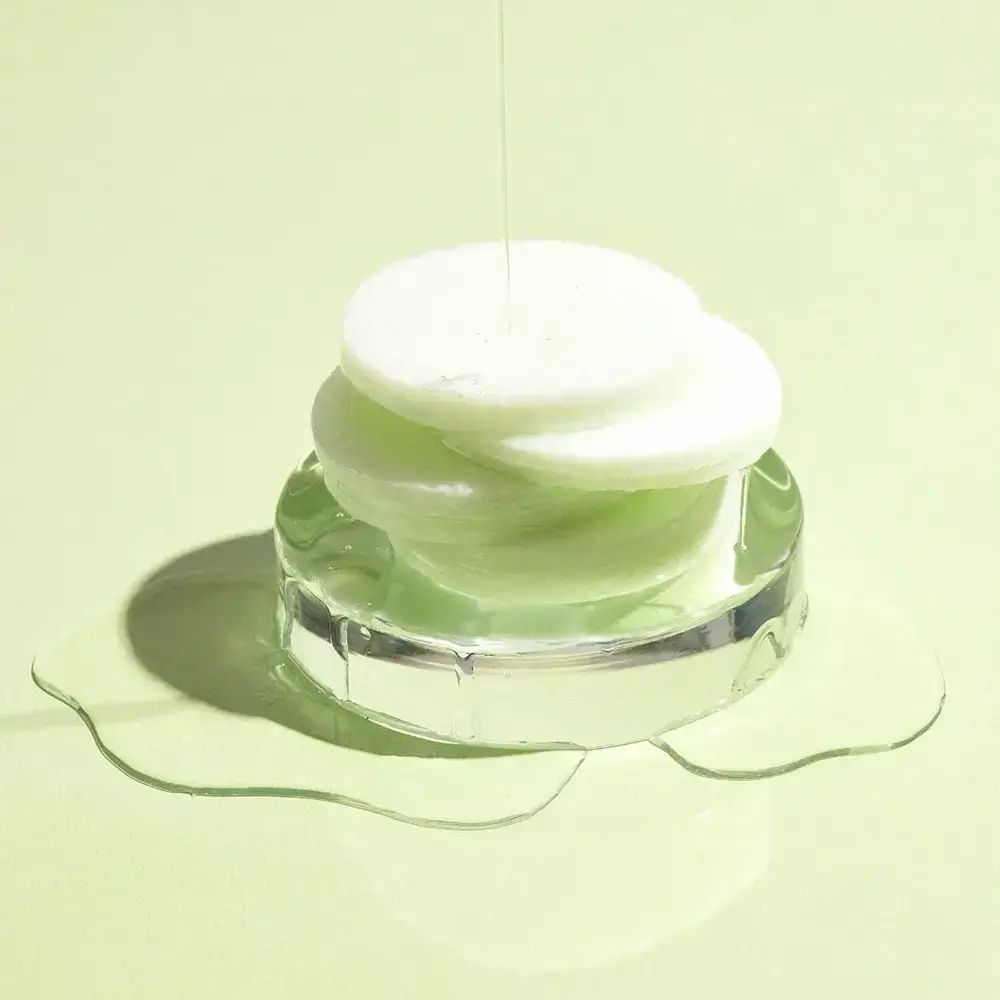 Dischetti verdi impilati su supporto trasparente. Liquido che gocciola sui dischetti.