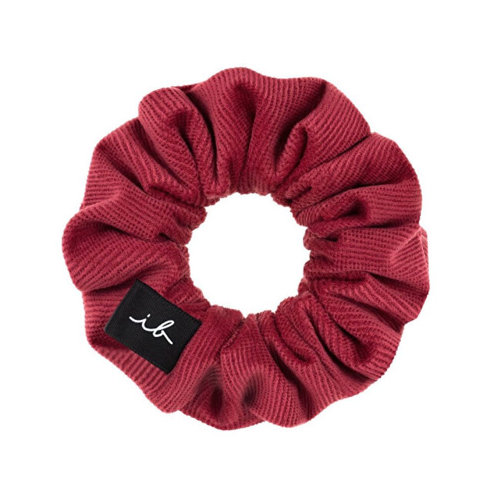 Scrunchie rosso. Marchio: invisibobble. Etichetta nera con 'ib'. Materiale a coste.