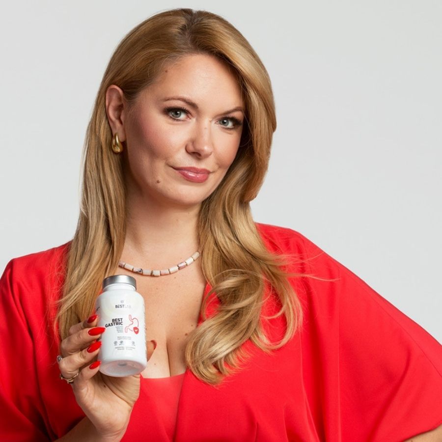 Donna tiene un flacone bianco, tappo grigio. Scritta: BEST LAB BEST GASTRIC. Simbolo stomaco rosso. La donna indossa un vestito rosso.