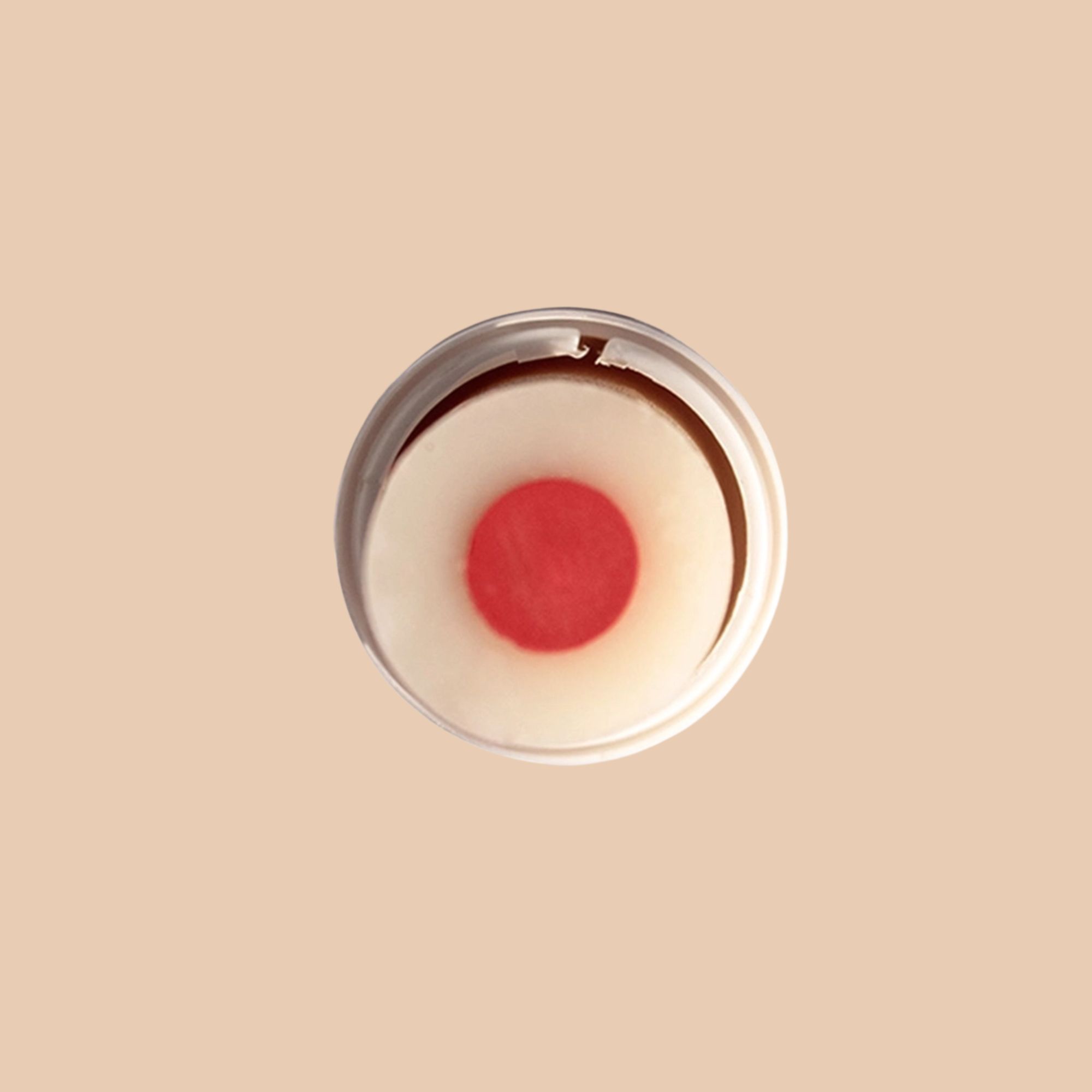 Balsamo labbra bicolore con cuore rosso. In contenitore trasparente, vista dall'alto.