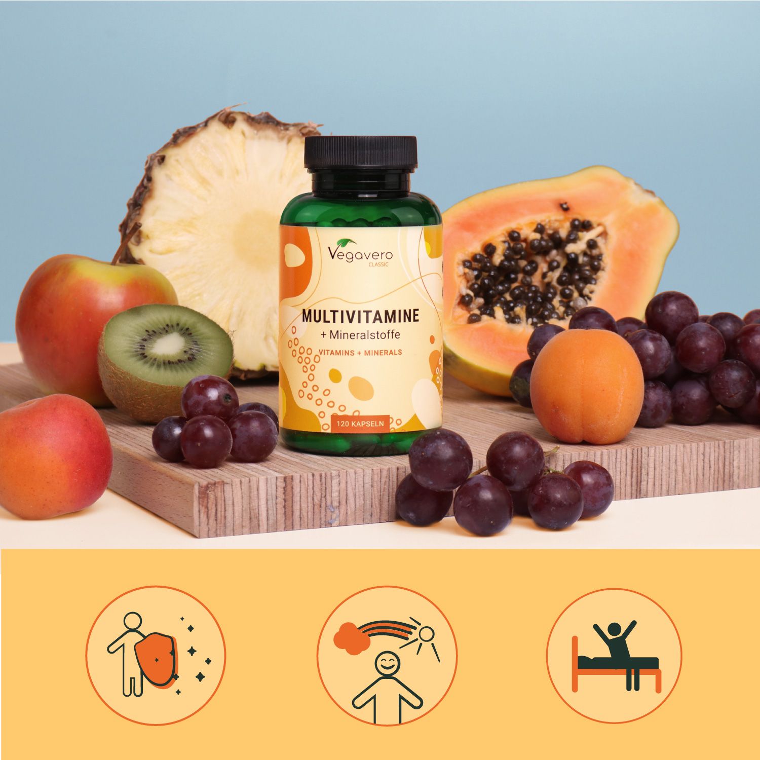 Una bottiglia di VEGAVERO Multivitamine + Minerali circondata da frutta: mela, kiwi, uva, papaya e albicocche. Su tagliere di legno.