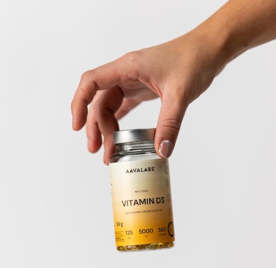 Mano che tiene un flacone di Aavalabs Vitamina D3 Softgels, 5000 UI.