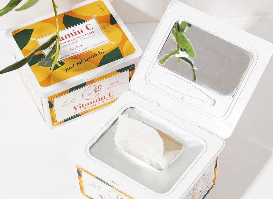Scatola di maschere aperta. Maschere all'interno. Specchio nel coperchio. Scritta: Vitamin C Daily Morning Care Mask.