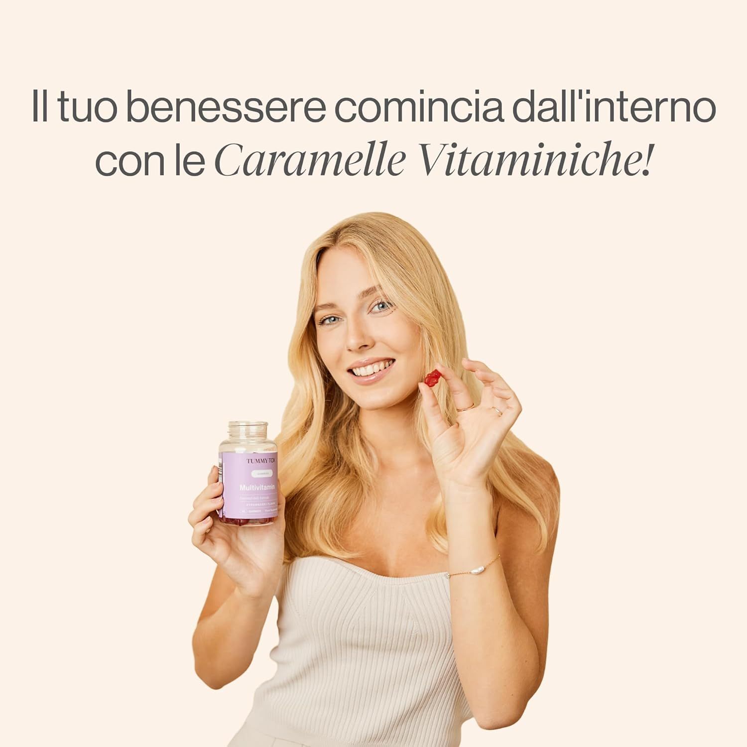 Donna che tiene una bottiglia e un orsetto gommoso. Testo: Caramelle gommose multivitaminiche.