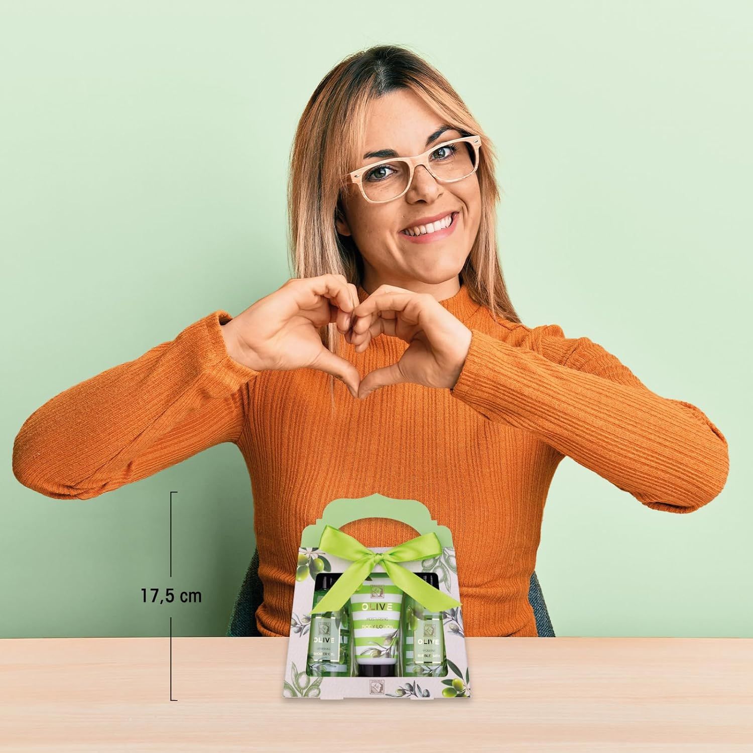 Donna tiene set regalo a forma di cuore. Set regalo con tre prodotti: gel doccia, lozione corpo, bagno schiuma. 17,5 cm.