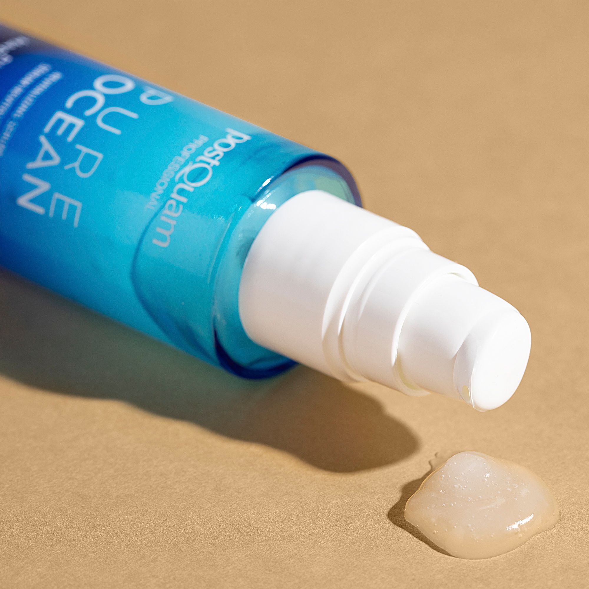 Flacone di siero sdraiato. Scritta: Postquam Pure Ocean. Goccia di siero su sfondo beige. Testina bianca.