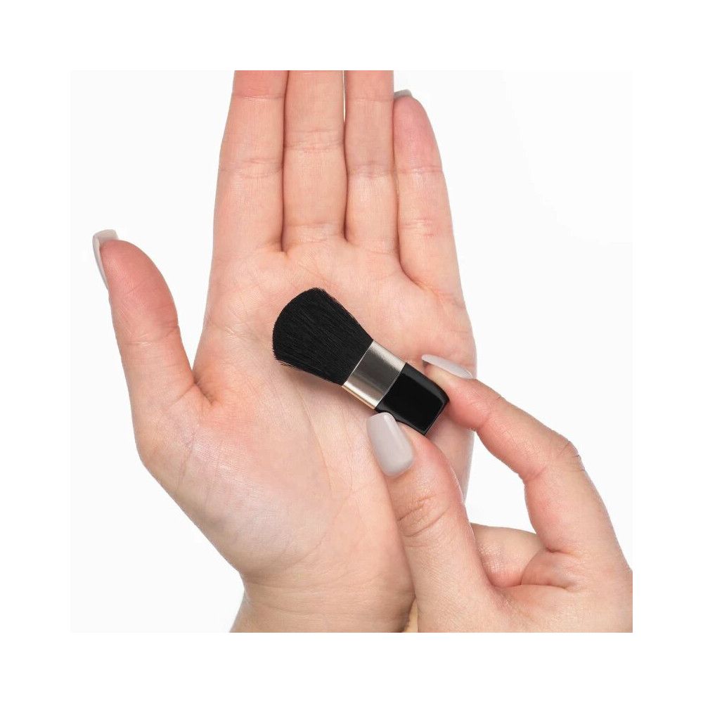 Pennello blush nero, ghiera argentata. Tenuto in una mano, l'altra mano tiene il pennello.