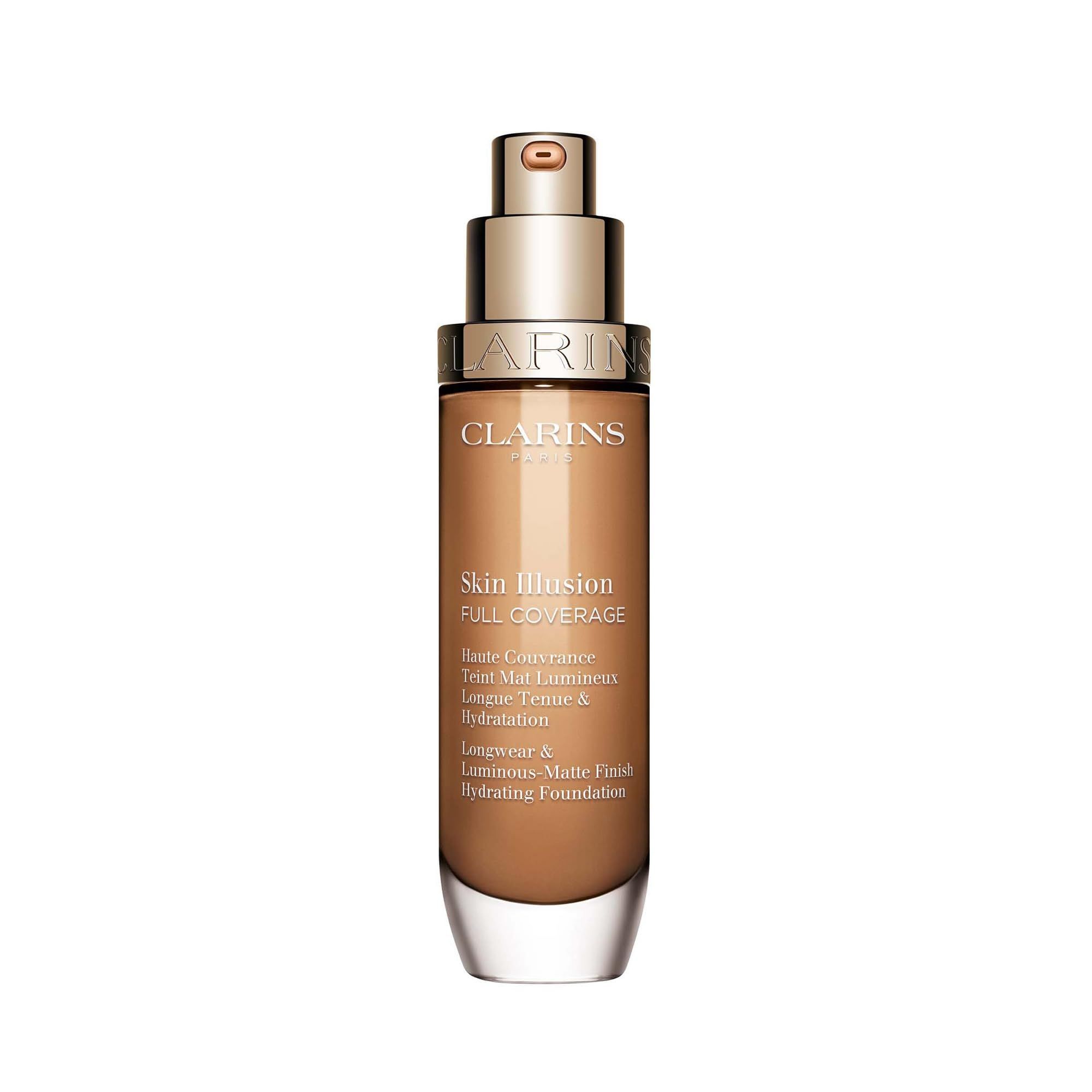 Clarins Skin Illusion Full Coverage Foundation. Flacone di vetro marrone con tappo dorato. Nome del prodotto e dettagli sull'etichetta.