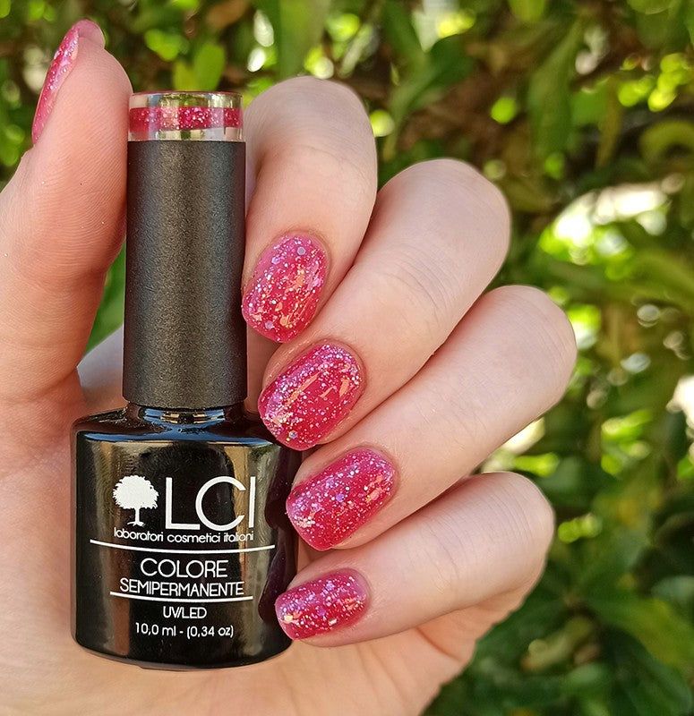 Flacone smalto in mano. Smalto rosa glitterato sulle unghie. Scritta: LCI, Colore Semipermanente, UVLED.