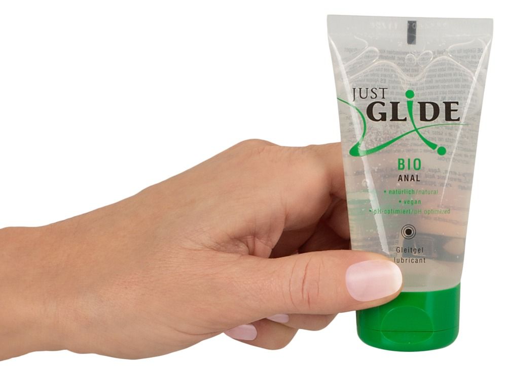 Mano che tiene un tubo con tappo verde. Scritta: JUST GLIDE BIO ANAL. Prodotto in confezione trasparente.