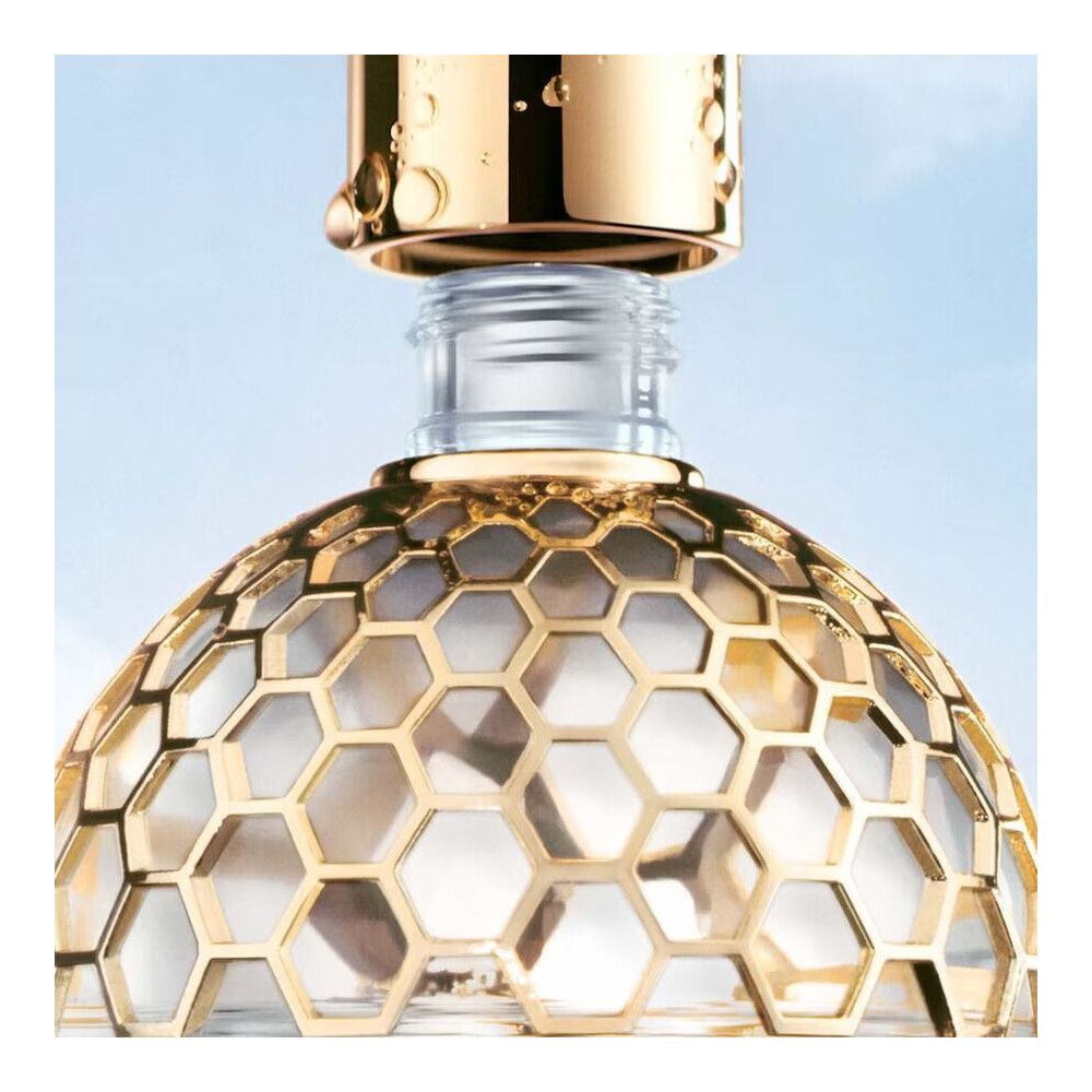 Flacone dorato con motivo a nido d'ape. Il tappo viene aperto. Bottiglia di vetro con tappo dorato.