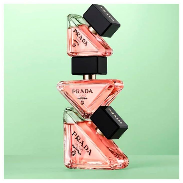 Tre flaconi di profumo rosa impilati. Tappi neri. Scritta PRADA.