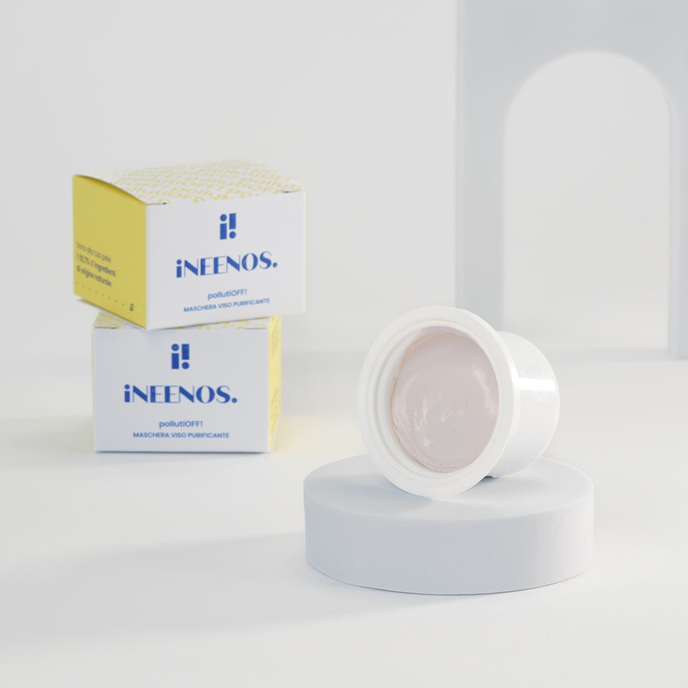 Due scatole gialle e una maschera bianca. Sulle scatole è scritto iNEENOS. pollutiOFF! Maschera con zeolite. Maschera su un piedistallo.