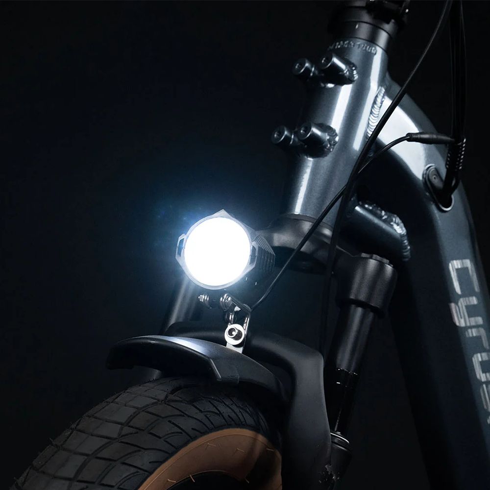 Parte anteriore della e-bike con faro acceso. Logo CYRUSHER non visibile.