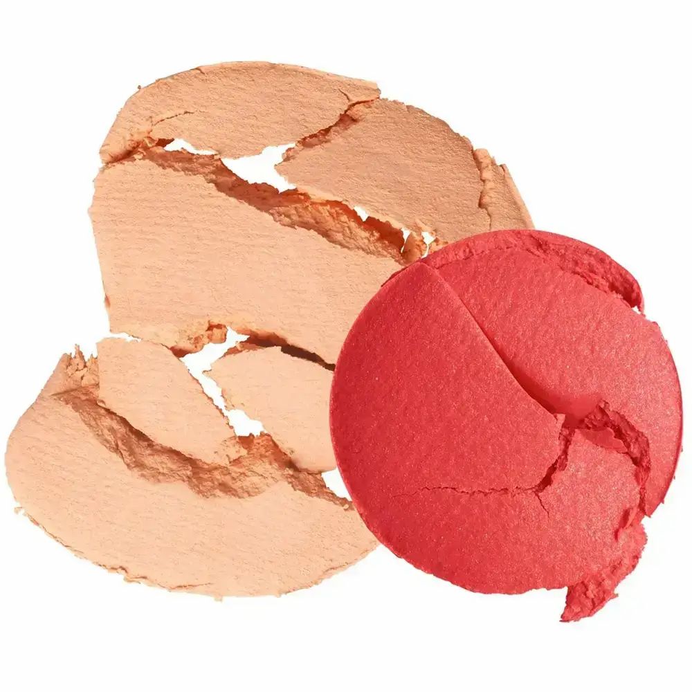 Due pezzi di fard rotti. Un pezzo color pesca, un pezzo rosso. Su sfondo bianco.