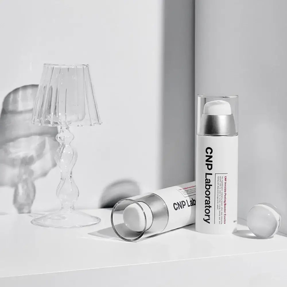 Due flaconi bianchi con erogatori argentati. Scritta: CNP Laboratory. Un flacone è sdraiato, l'altro in piedi.