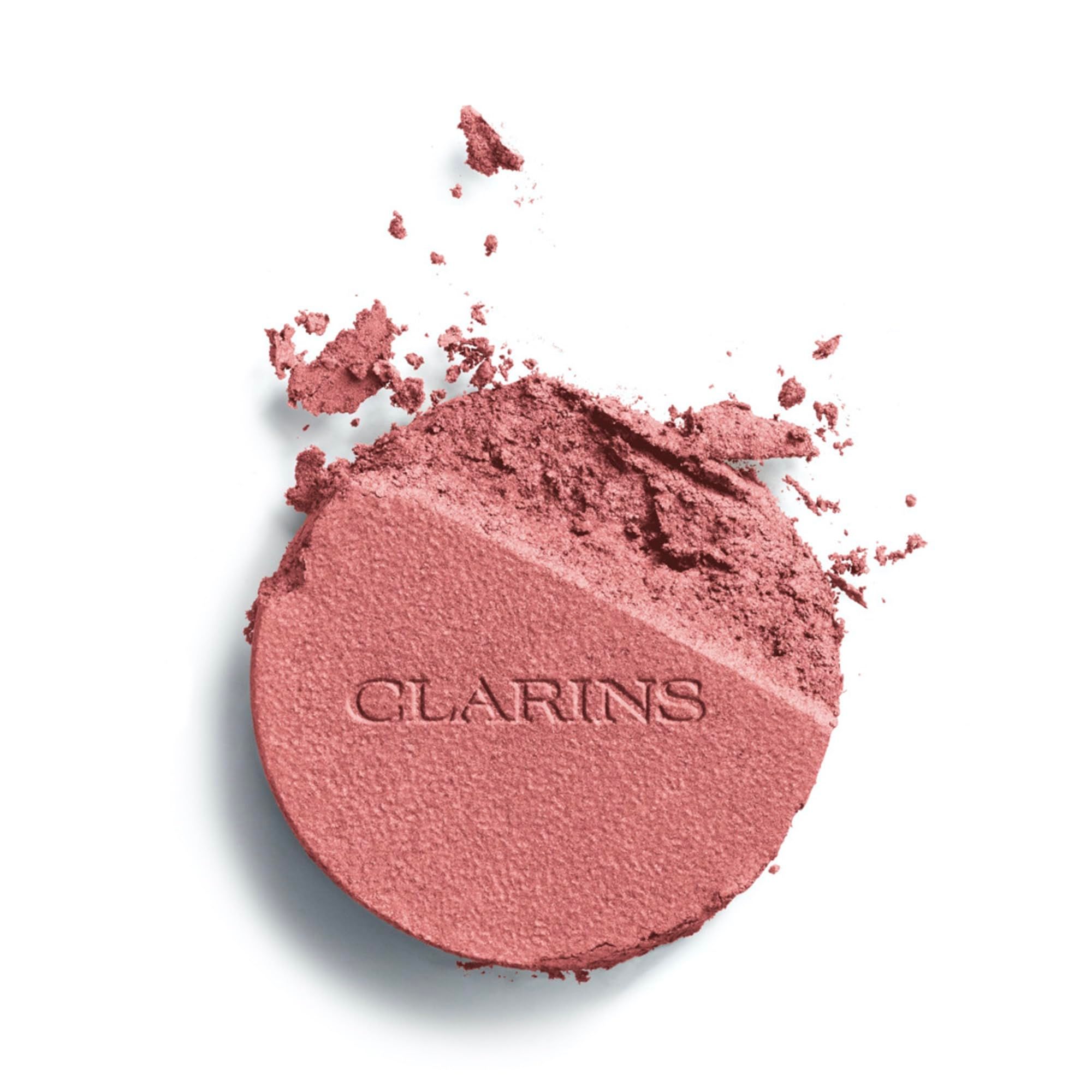 Polvere di blush frantumata, divisa a metà. Una metà rosa, l'altra polverizzata. Logo Clarins impresso.