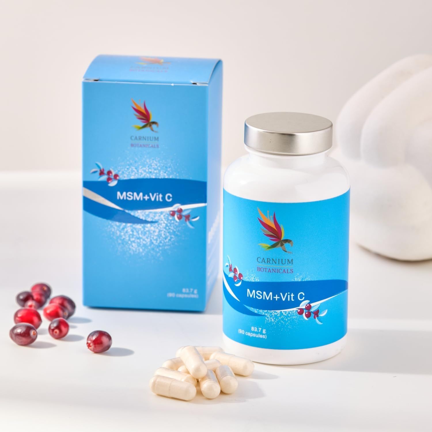 Scatola e flacone blu e bianco "MSM+Vit C" con capsule e mirtilli rossi.
