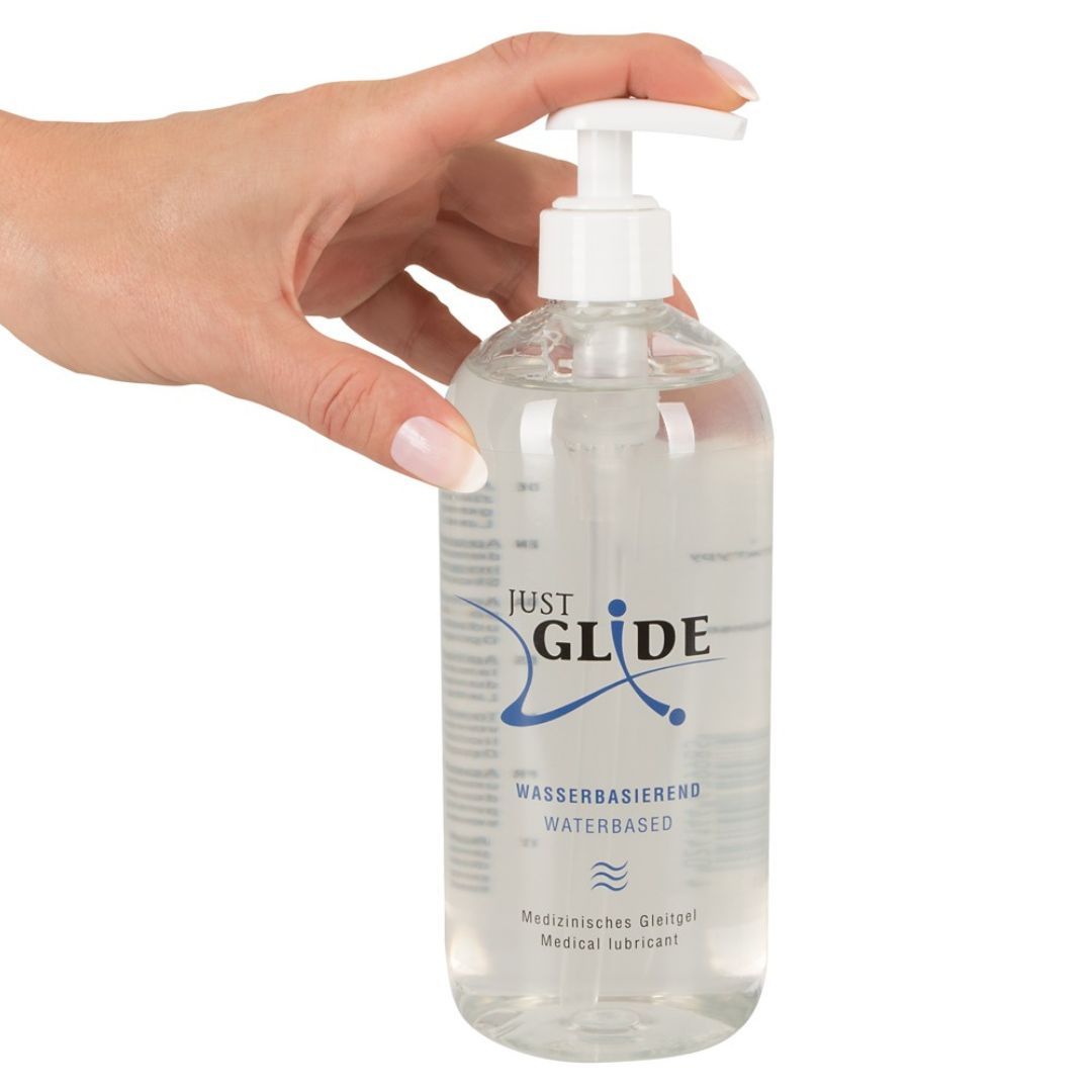 Mano che tiene un flacone trasparente con dosatore. Scritta: JUST GLIDE, a base d'acqua, gel lubrificante medico.