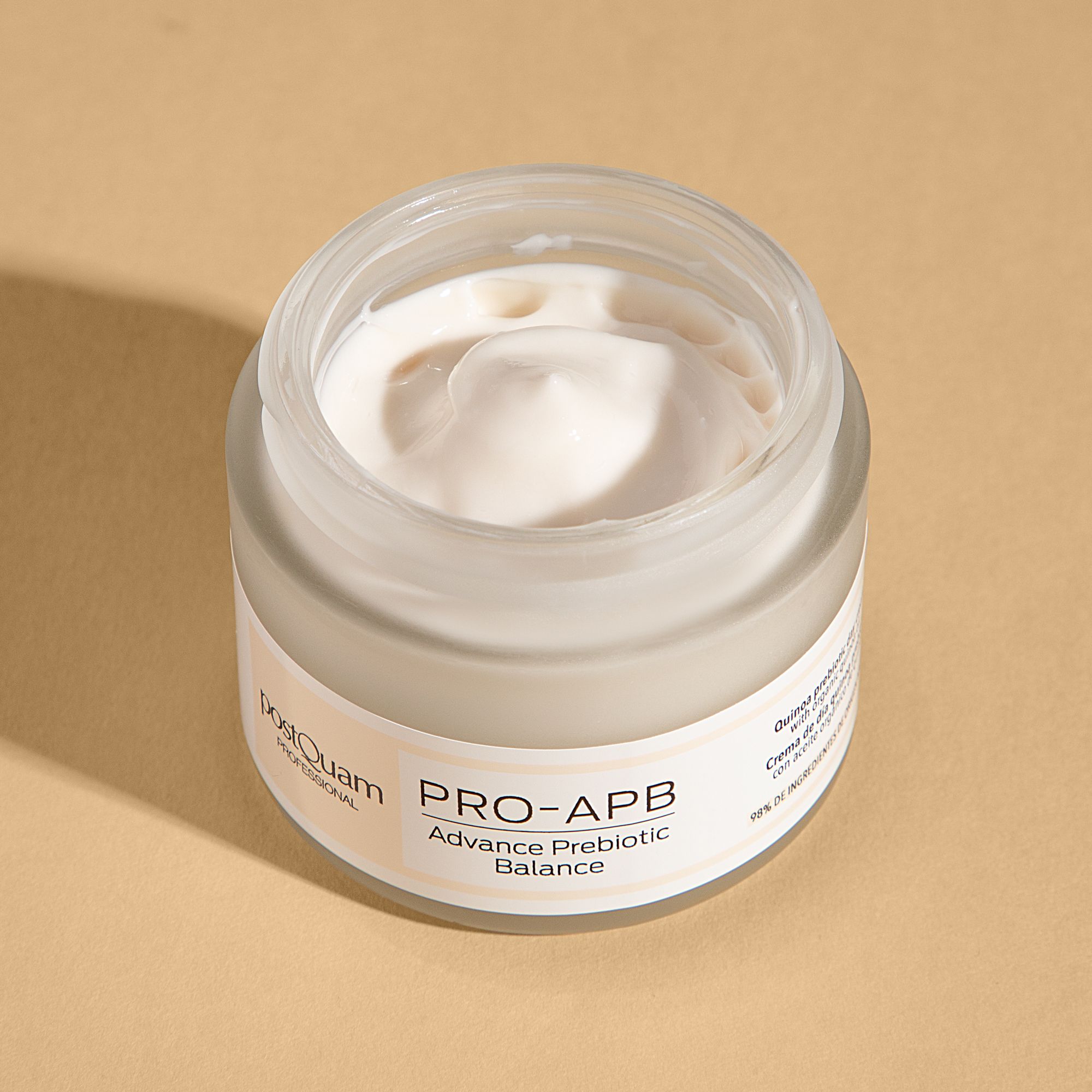 Vasetto di crema aperto. Scritta: PRO-APB Advance Prebiotic Balance. Marchio: postQuam. Crema visibile. Sfondo beige.