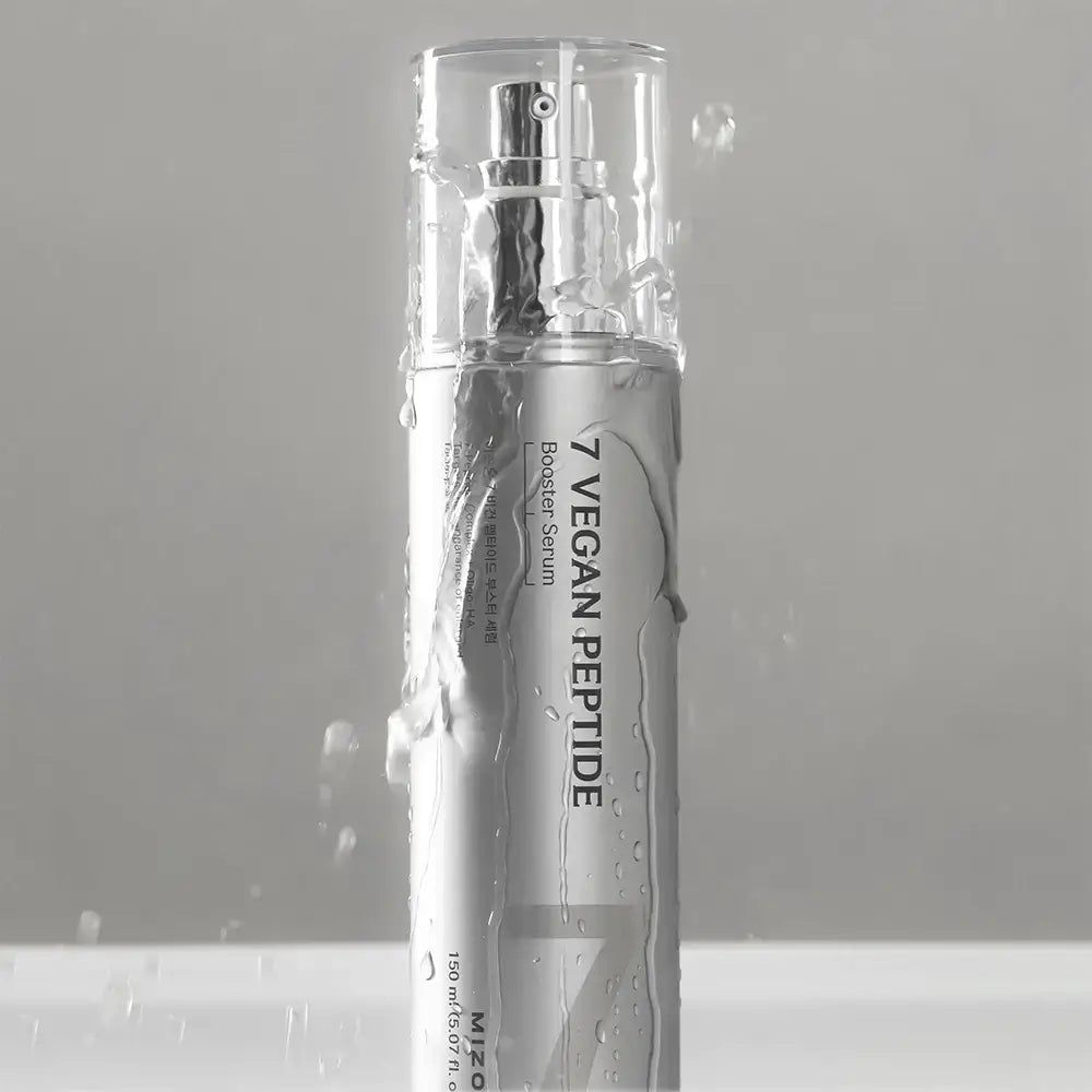Flacone d'argento con vaporizzatore. Scritta "7 Vegan Peptide Booster Serum". L'acqua schizza sul flacone. Tappo trasparente.