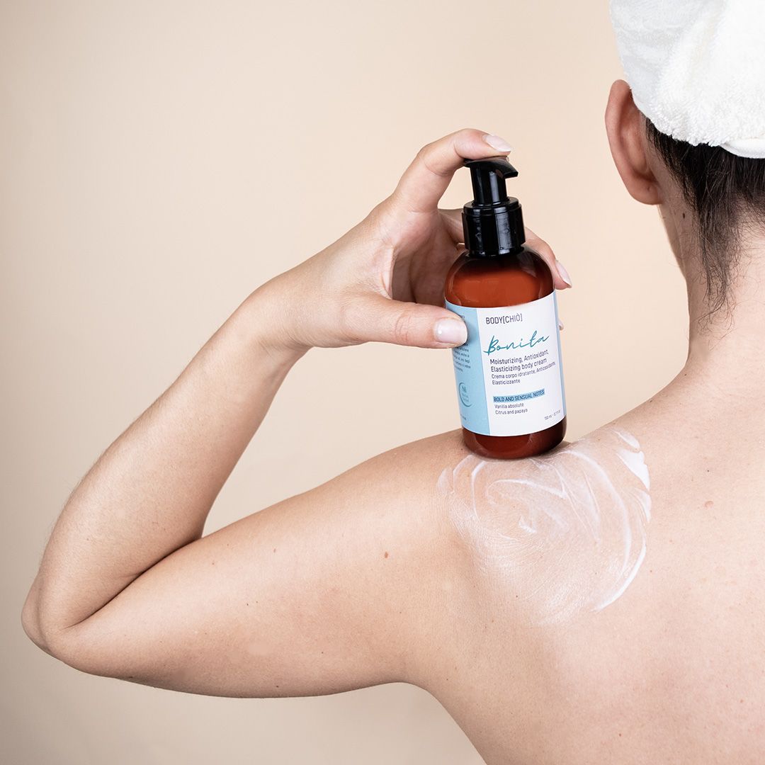 Flacone marrone con dosatore nero. Scritta Bonita. Crema applicata sulla spalla.