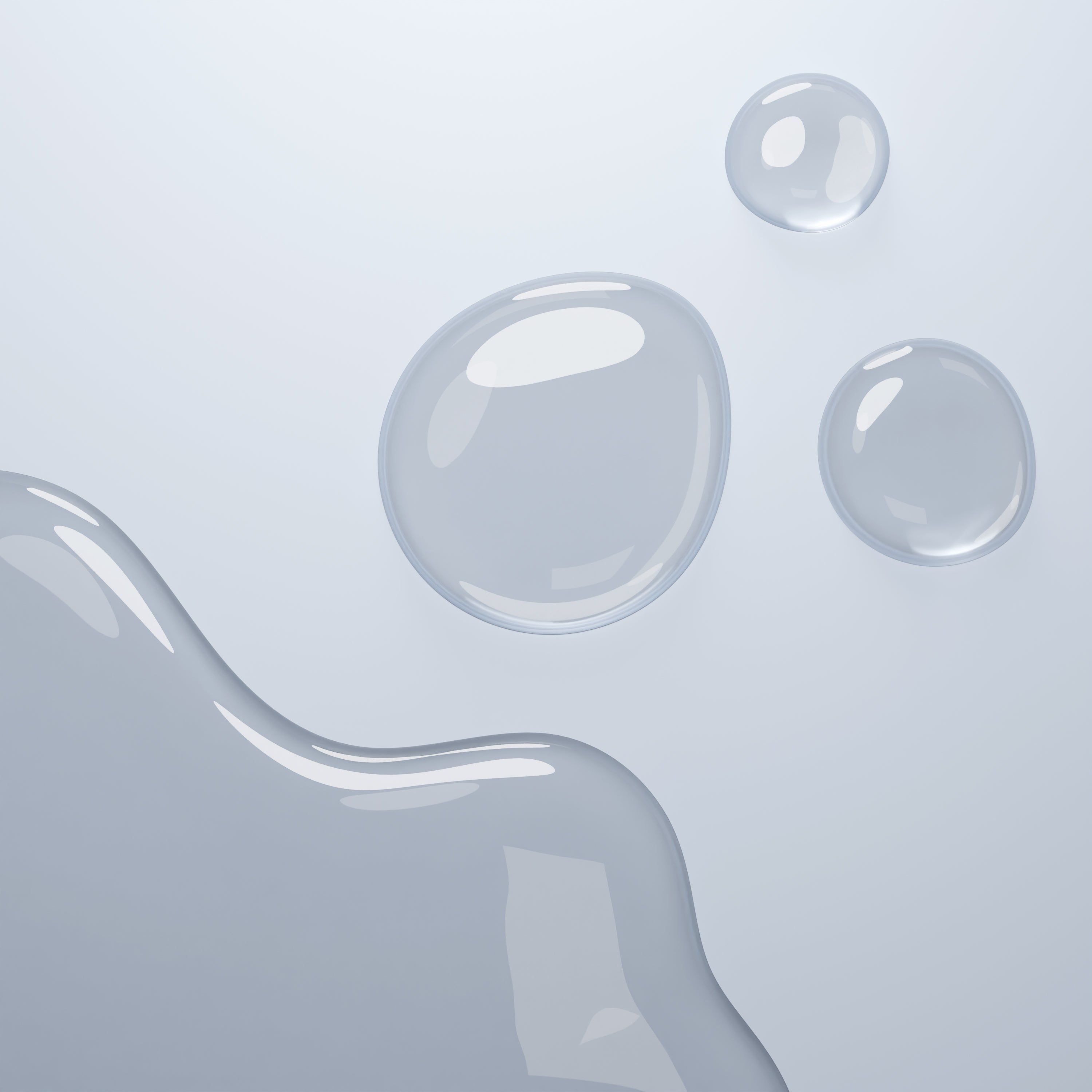 Tre gocce di liquido su sfondo chiaro. Il liquido è trasparente e lucido.