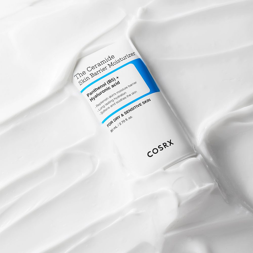 COSRX The Ceramide Skin Barrier Moisturizer in tubo bianco, circondato da crema bianca.