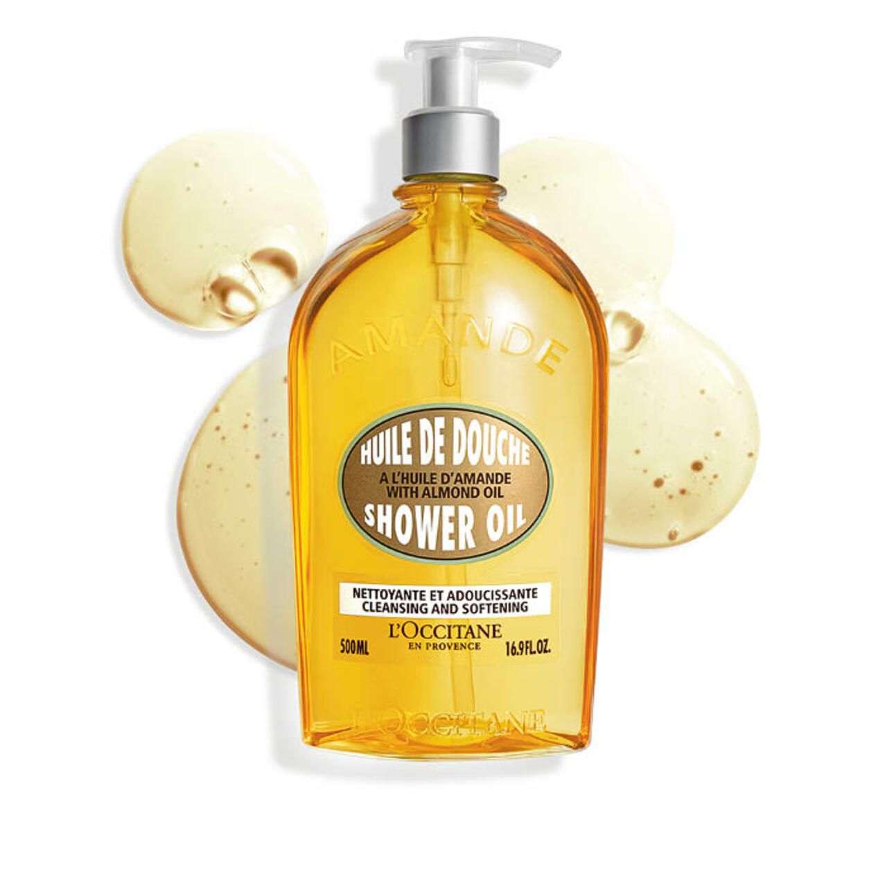 Flacone giallo con pompa. Scritta: Huile de Douche, Shower Oil, L'Occitane. Gocce giallastre accanto.