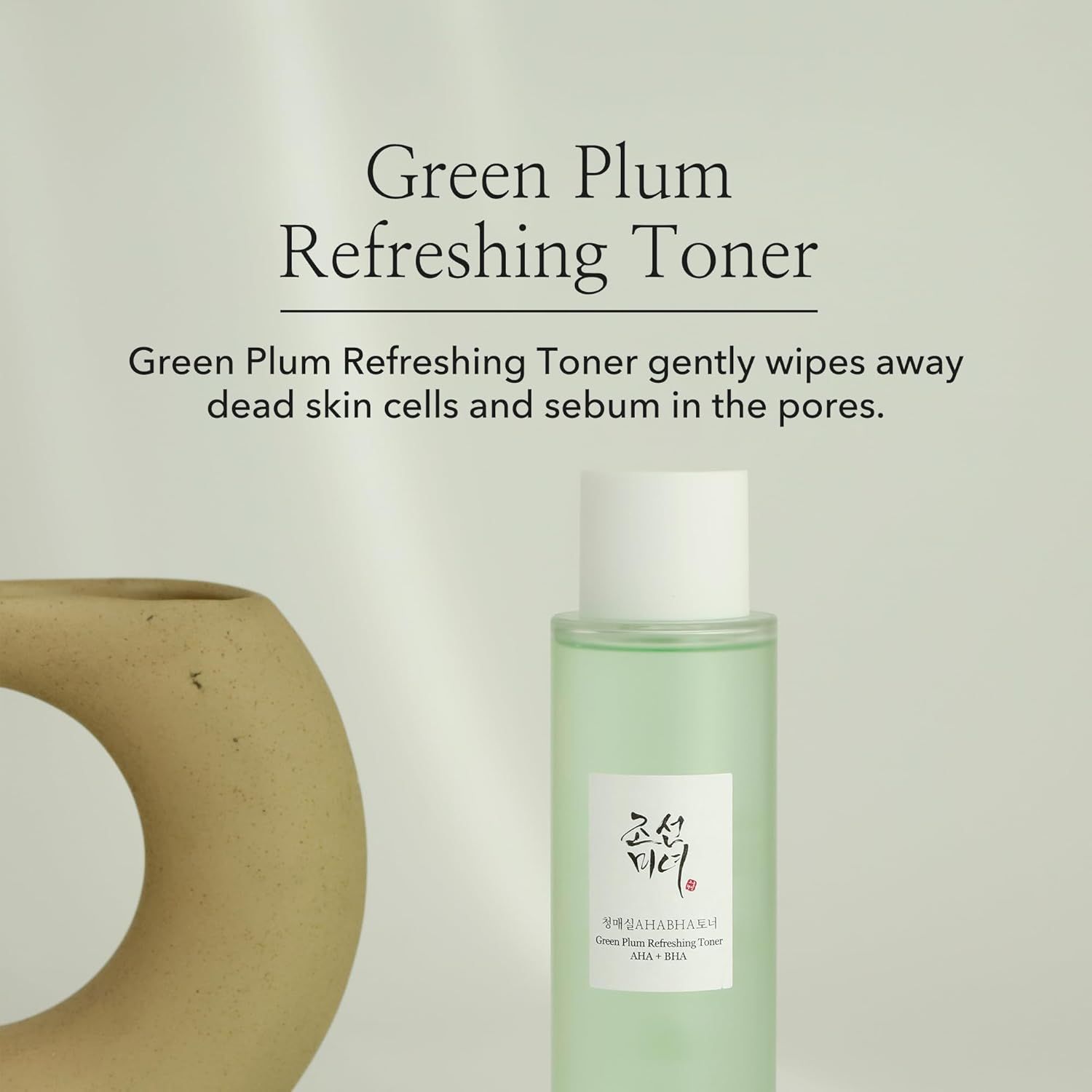 Flacone di toner accanto a un oggetto decorativo. Testo: Green Plum Refreshing Toner. Descrizione: rimuove le cellule morte e il sebo.