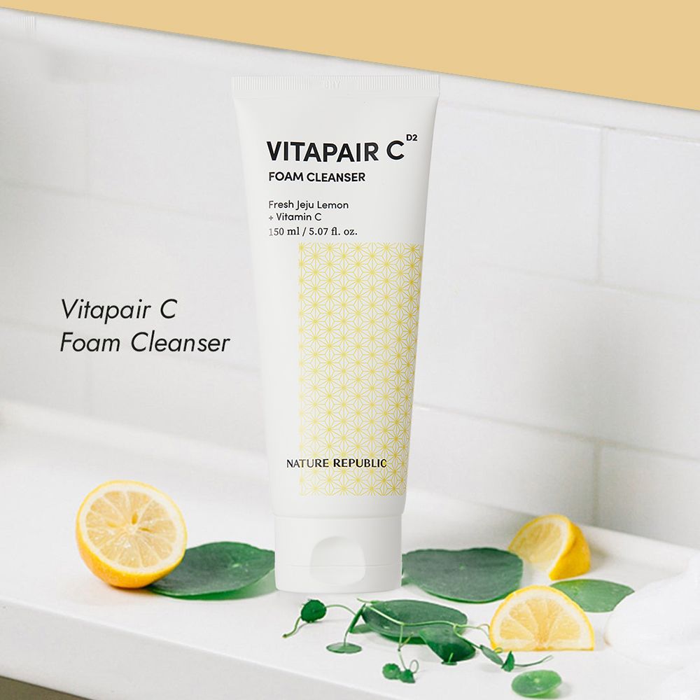 Tubo bianco di Vitapair C Foam Cleanser. Su una superficie bianca con limoni e foglie. Testo: NATURE REPUBLIC, VITAPAIR C.