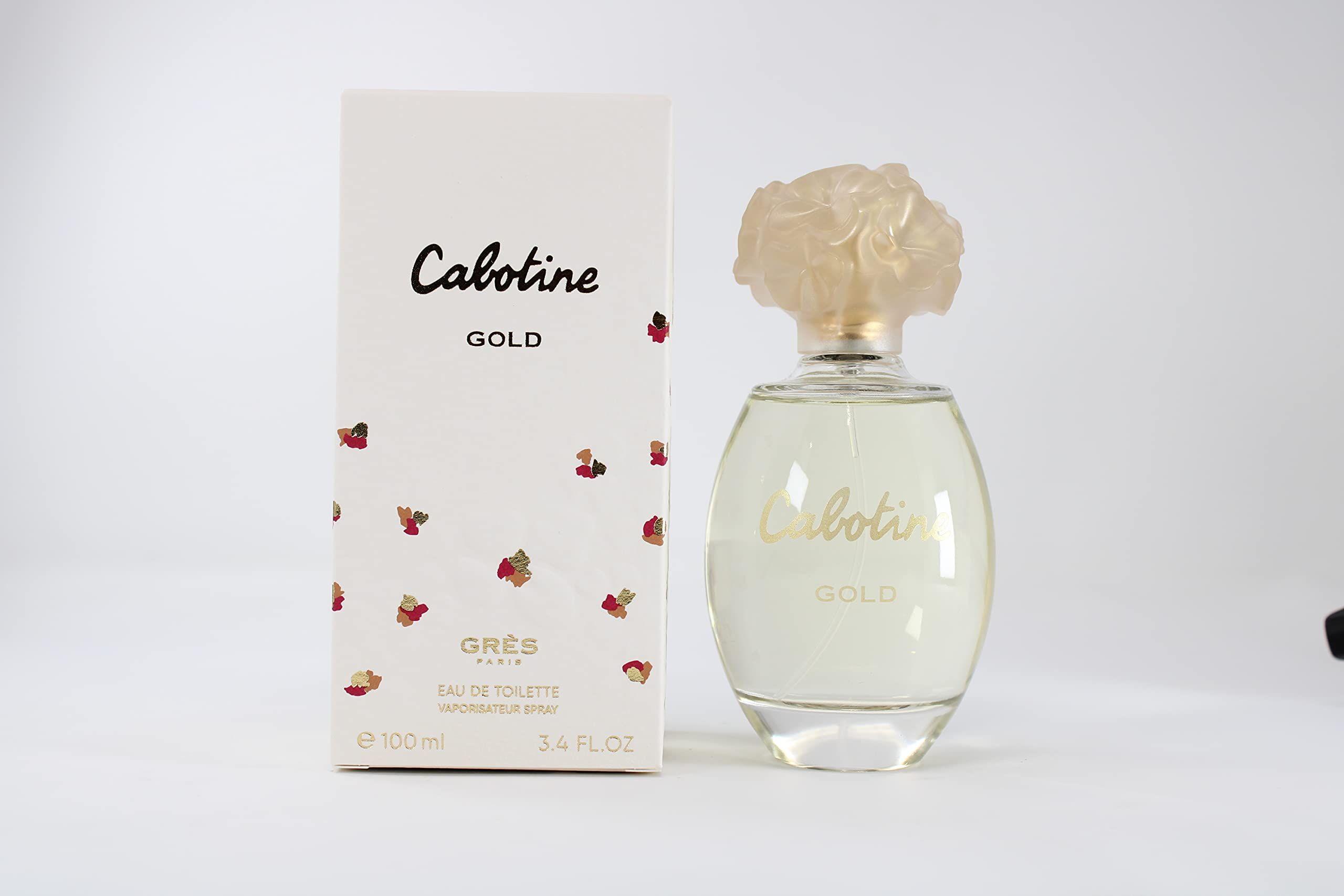 Flacone di profumo e confezione. Flacone con tappo e scritta dorati. Confezione con scritta e motivo floreale.