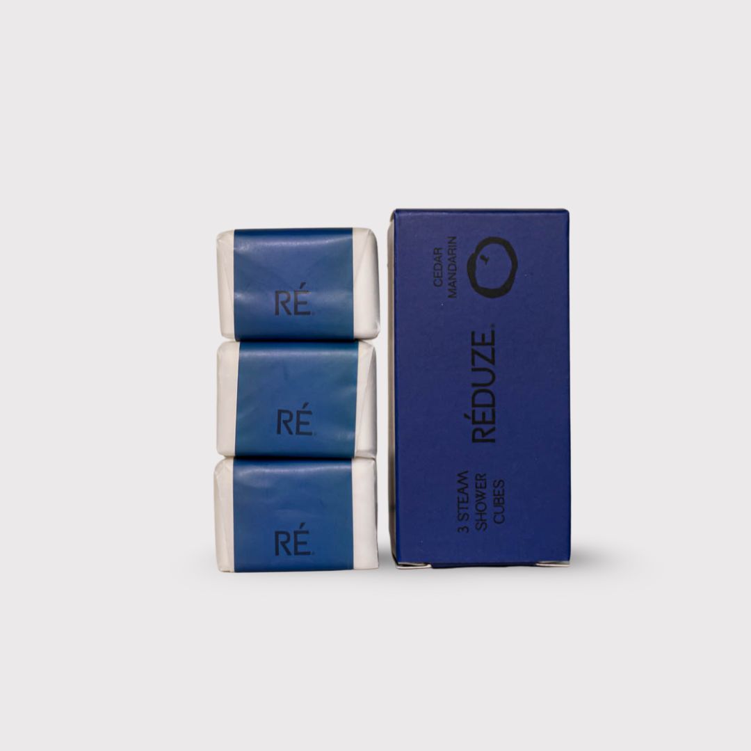 Tre cubetti doccia confezionati e una scatola blu. Scritta RÉDUZE. Profumo Cedro Mandarino. 3 Steam Shower Cubes.