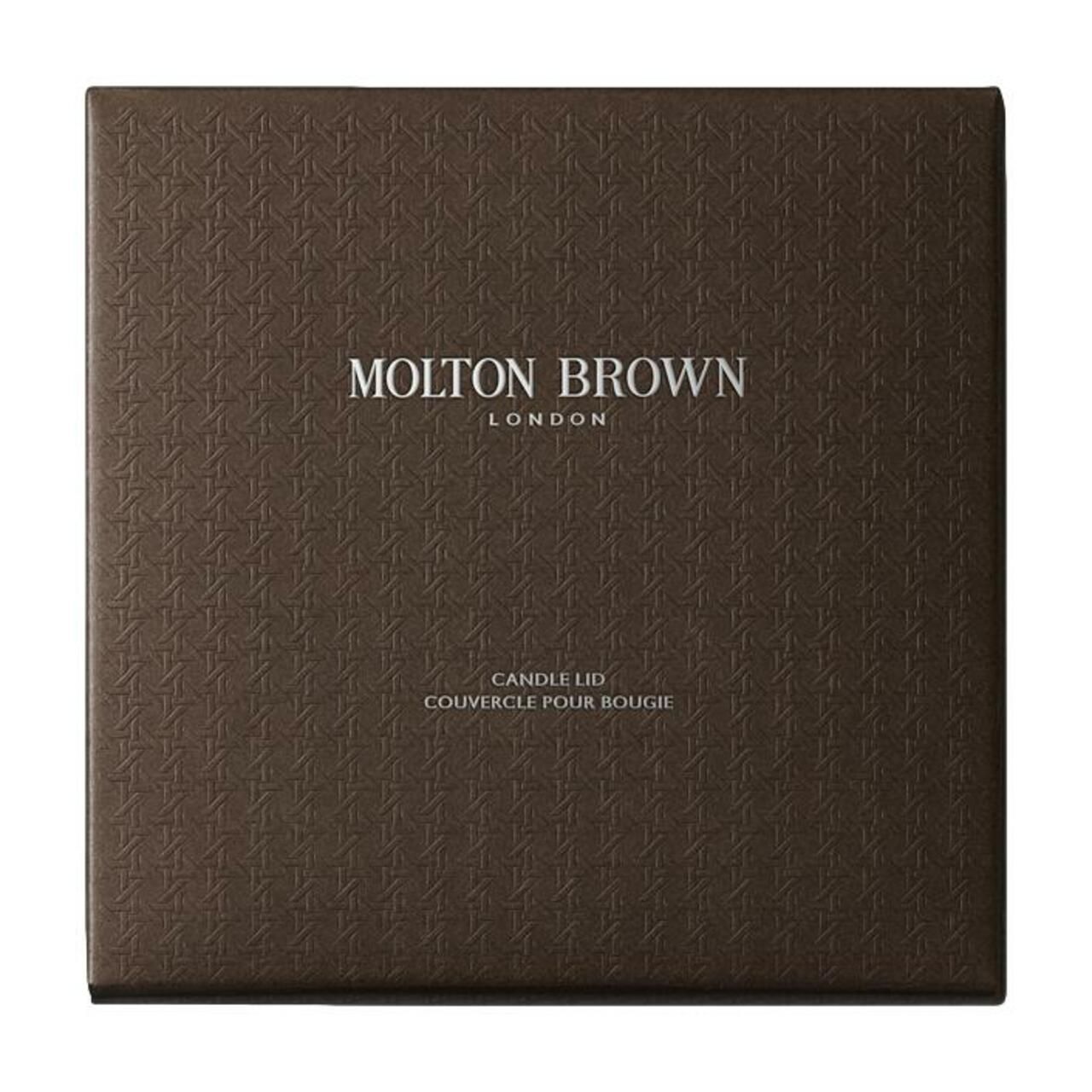 Scatola quadrata marrone con motivo in rilievo. "Molton Brown London" e "Candle Lid / Couvercle pour Bougie" sono visibili.