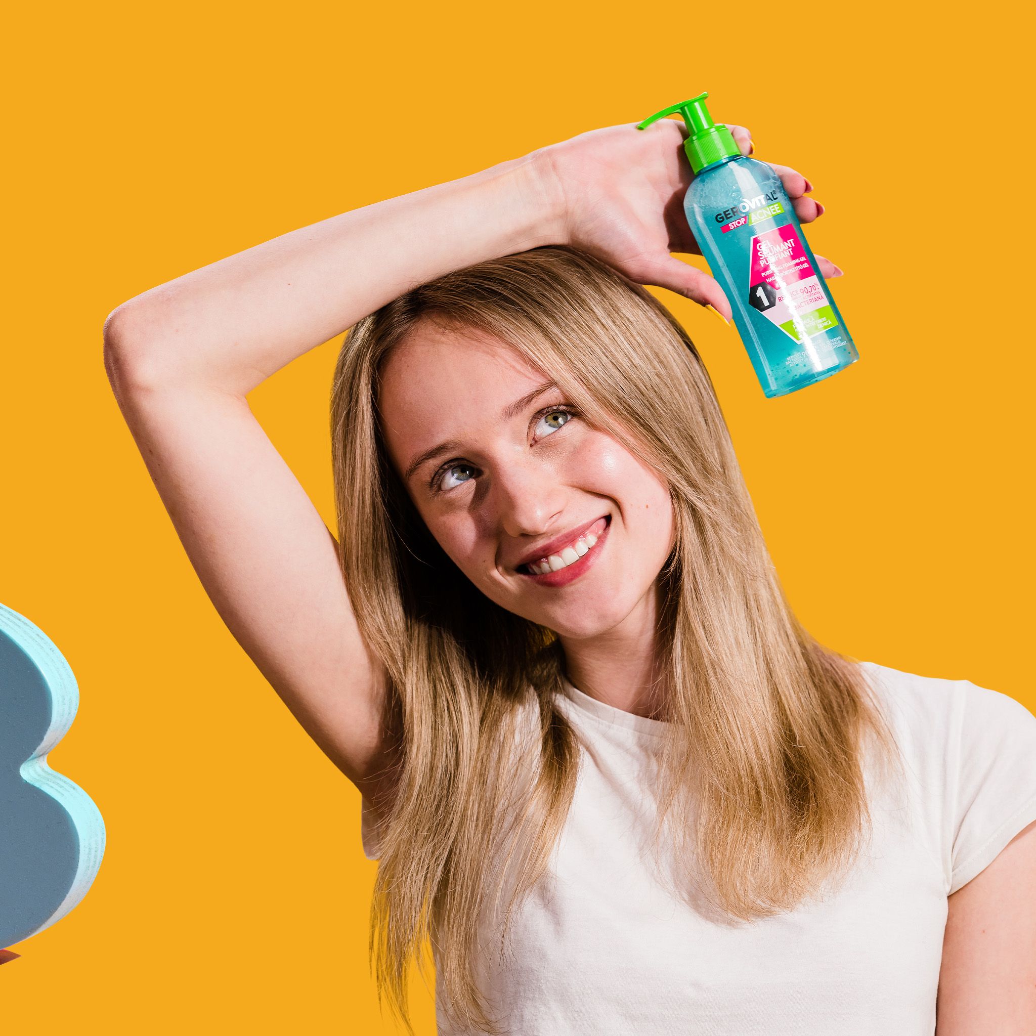 Una donna tiene in alto un flacone. Il gel viene applicato sulla mano. Sfondo giallo-arancio.