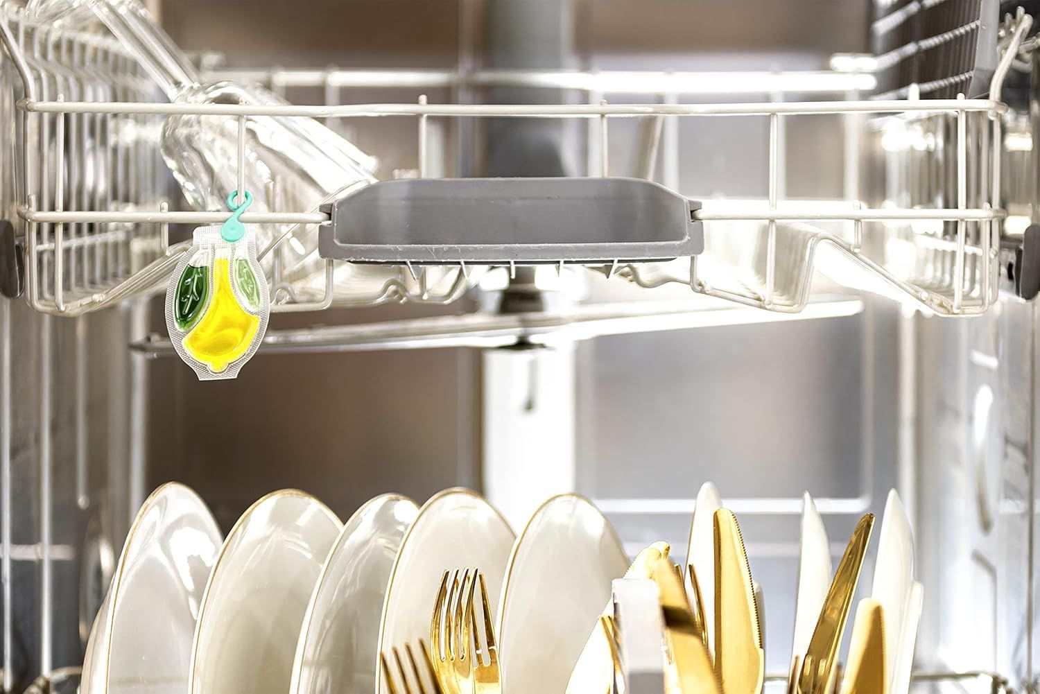 Lavastoviglie con piatti e posate. Un deodorante è appeso nella parte superiore della lavastoviglie.